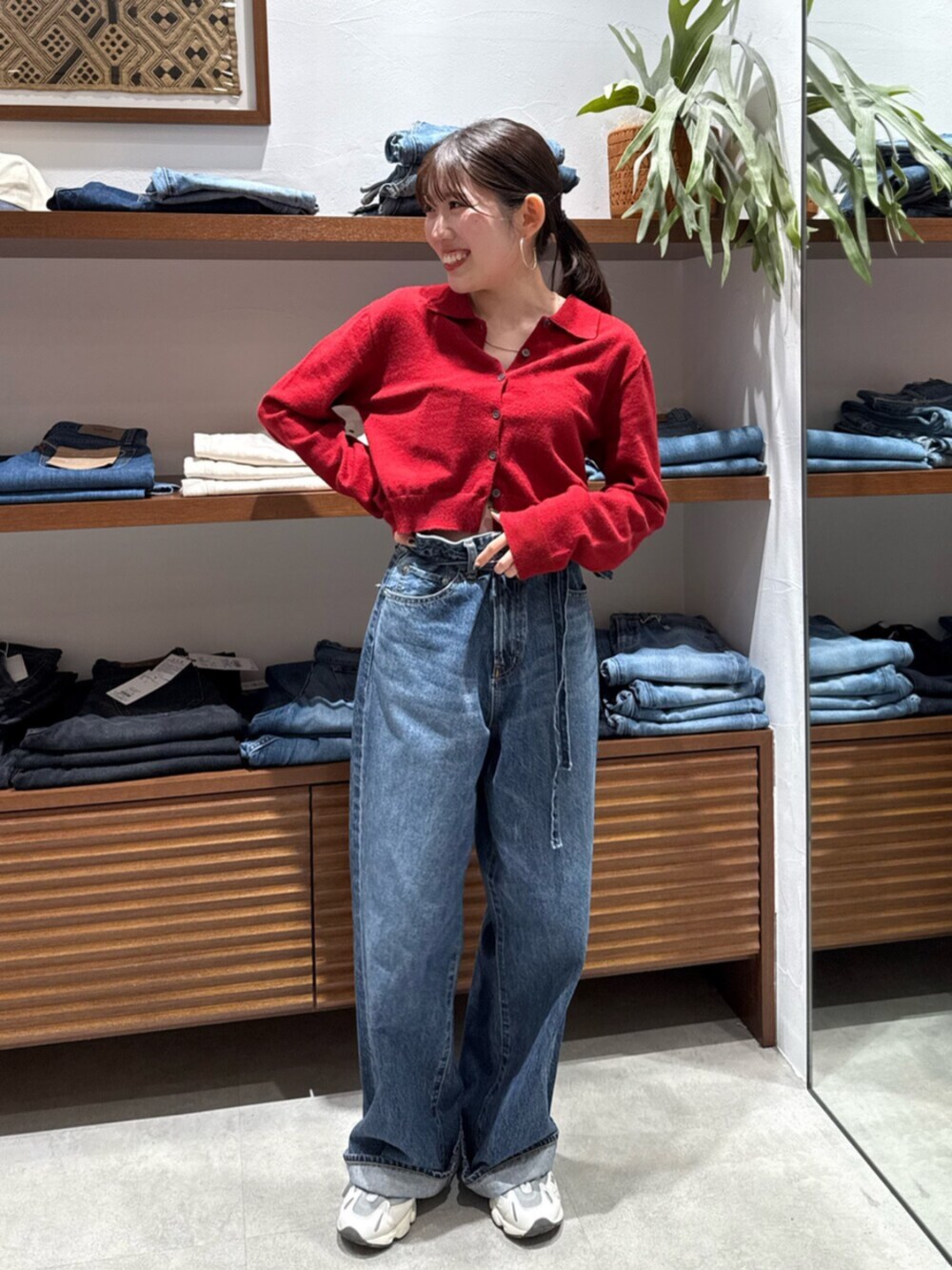 レッド系のカーディガン/ボレロ、ブルー系のデニムパンツを着用したレディースの秋コーディネートの3枚目の写真