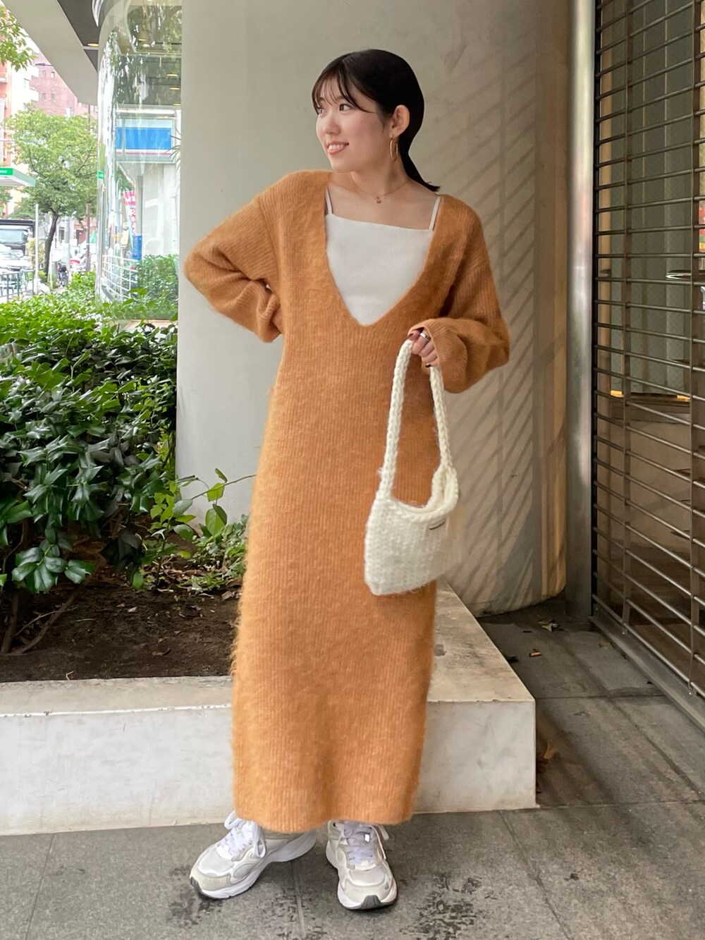 ホワイト系のハンドバッグ、オレンジ系のワンピースを着用したレディースの秋コーディネートの6枚目の写真