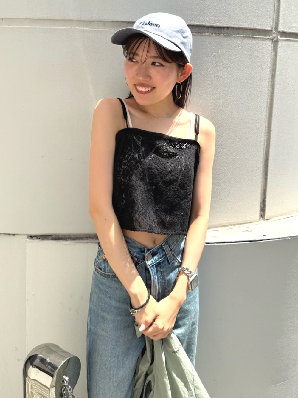 ブラック系のサンダル、グリーン系のトートバッグ、ブルー系のデニムパンツを着用したレディースの夏コーディネートの7枚目の写真