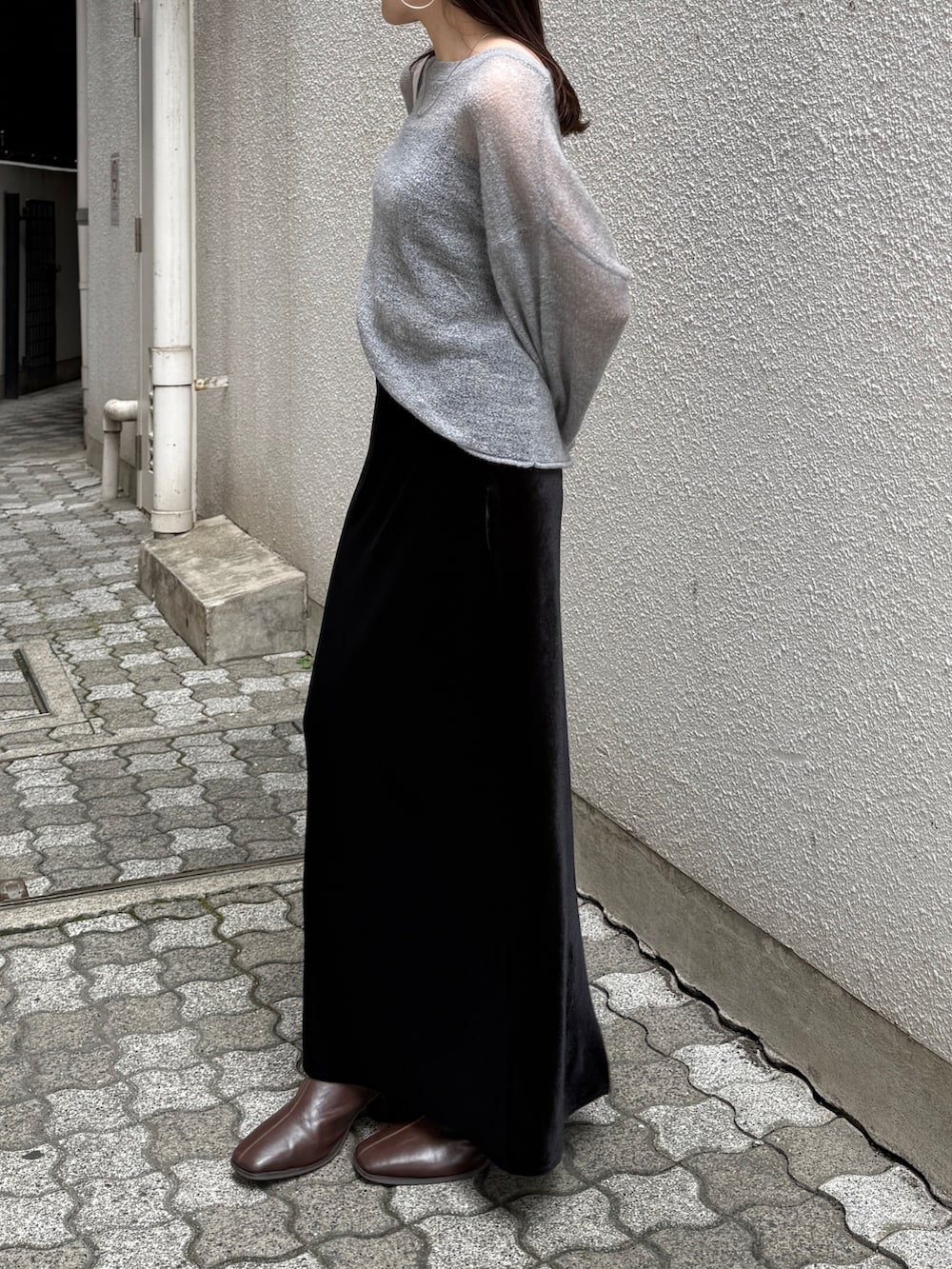 ブラック系のスカート、ブラウン系のブーツ、グレー系のニット/セーターを着用したレディースの秋コーディネートの3枚目の写真