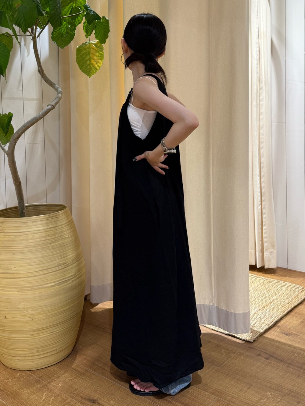 ブラック系のワンピース、ブルー系のデニムパンツ、ブラック系のサンダルを着用したレディースの夏コーディネートの2枚目の写真