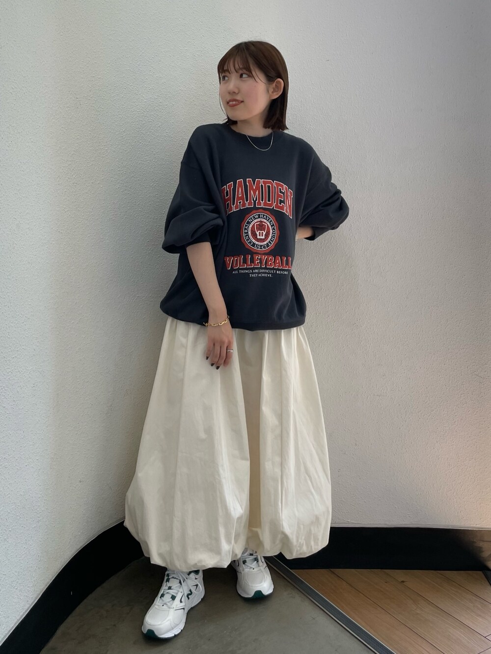 グレー系のスウェット、ホワイト系のスカート、グリーン系のスニーカーを着用したレディースの夏コーディネートの3枚目の写真