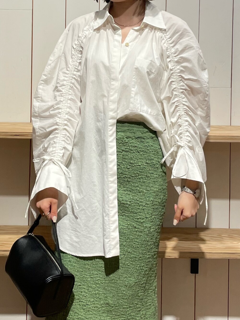 ブラック系のハンドバッグ、ブラック系のブーツ、ホワイト系のシャツ/ブラウスを着用したレディースの冬コーディネートの4枚目の写真