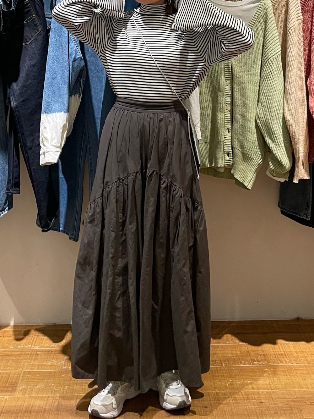 グレー系のスカート、ホワイト系のニット/セーター、シルバー系のショルダーバッグを着用したレディースの冬コーディネートの3枚目の写真