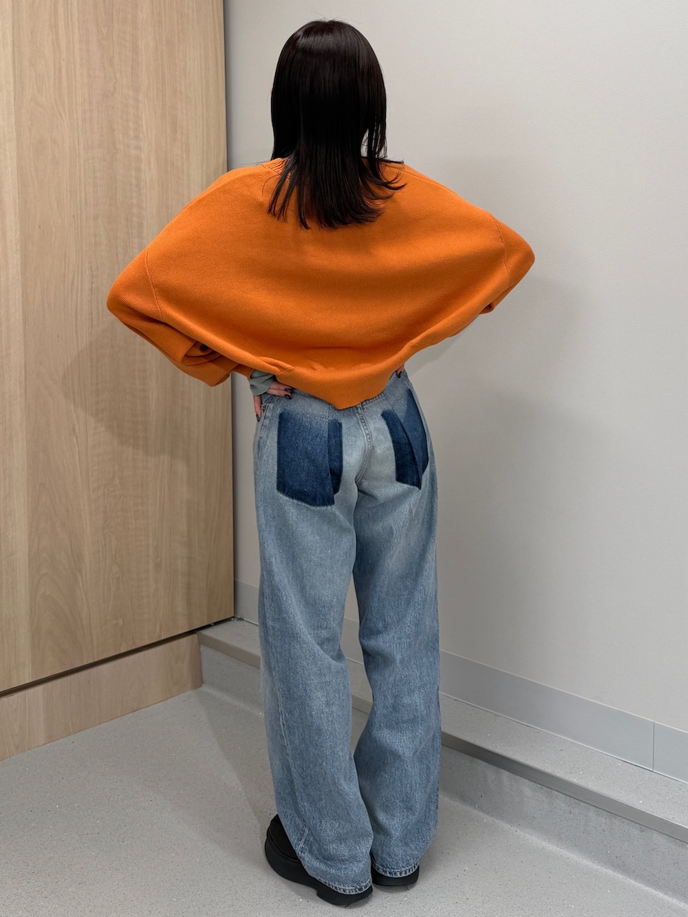 ブルー系のデニムパンツ、オレンジ系のニット/セーター、ブラック系のブーツを着用したレディースの冬コーディネートの2枚目の写真