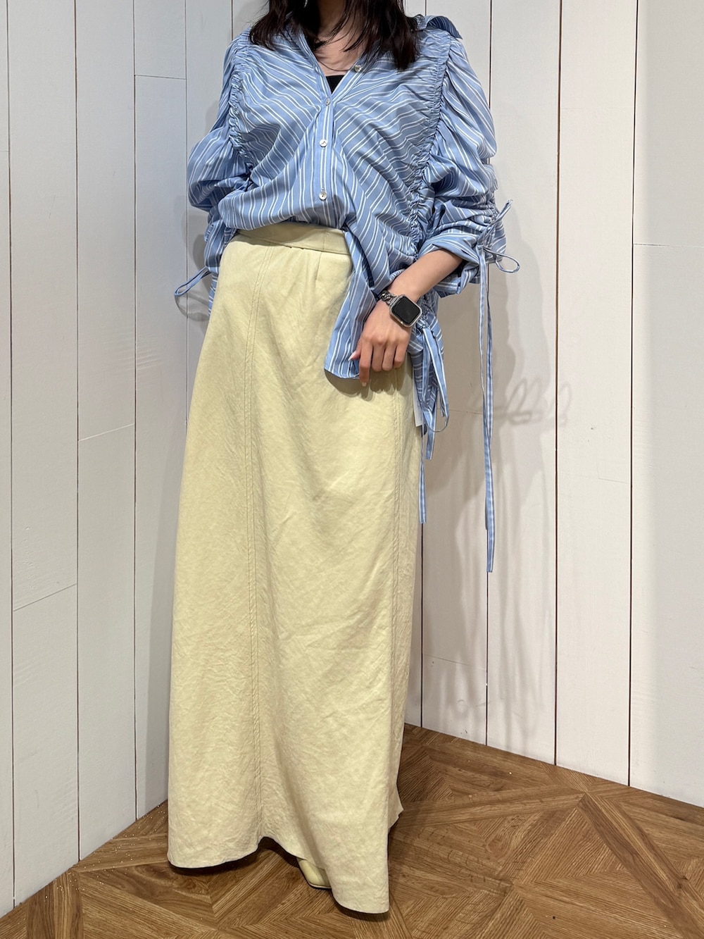 イエロー系のスカート、イエロー系のサンダル、ブルー系のシャツ/ブラウスを着用したレディースの春コーディネートの2枚目の写真