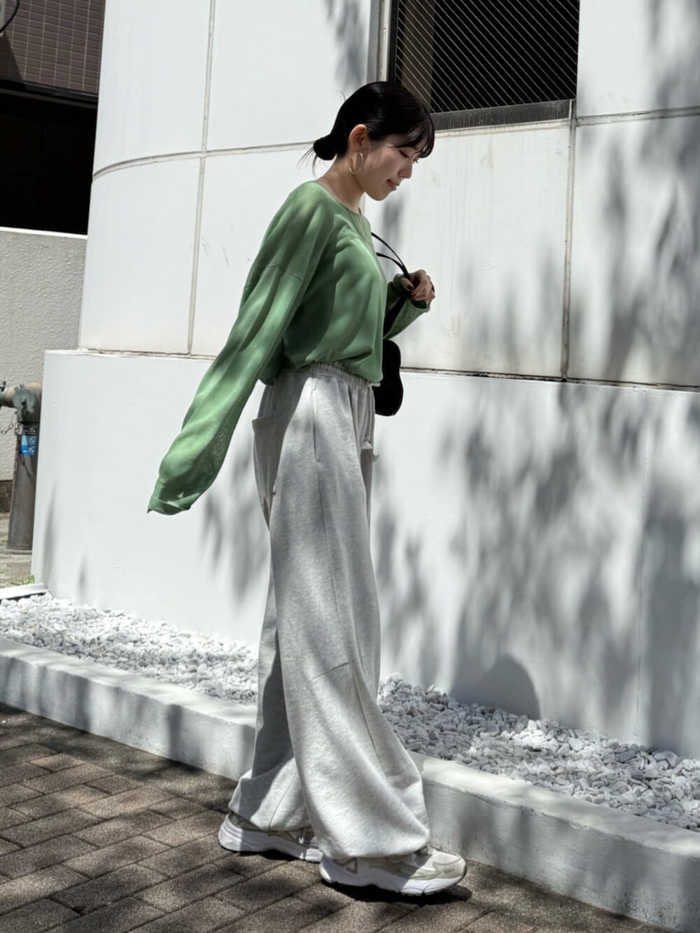 グレー系のスウェットパンツ、ブラック系のハンドバッグ、グリーン系のニット/セーターを着用したレディースの春コーディネートの5枚目の写真