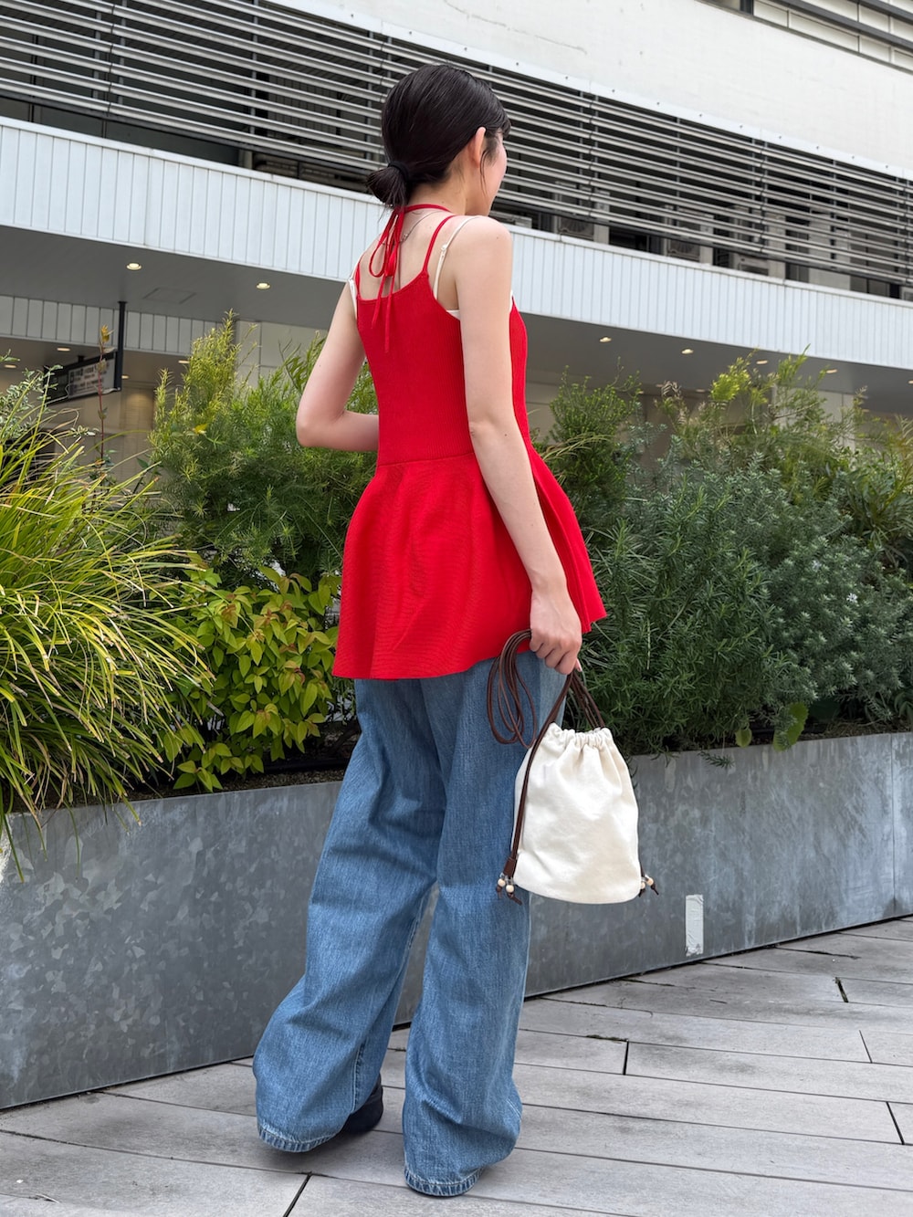 レッド系のキャミソール、ブルー系のデニムパンツ、ブラック系のブーツを着用したレディースの春コーディネートの6枚目の写真