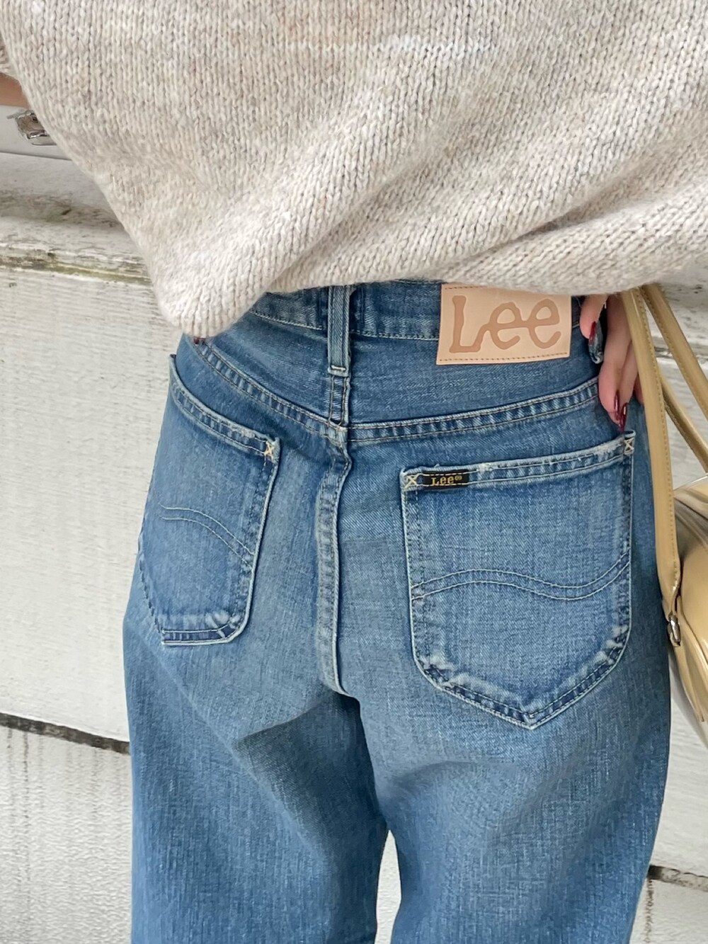 ブルー系のデニムパンツ、ブラウン系のブーツ、ベージュ系のハンドバッグを着用したレディースの秋コーディネートの10枚目の写真