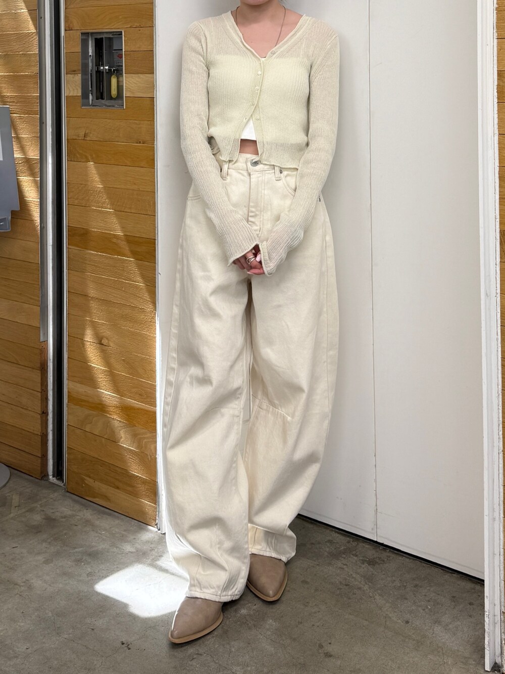 ホワイト系のデニムパンツ、ベージュ系のブーツ、ホワイト系のカーディガン/ボレロを着用したレディースの春コーディネートの2枚目の写真