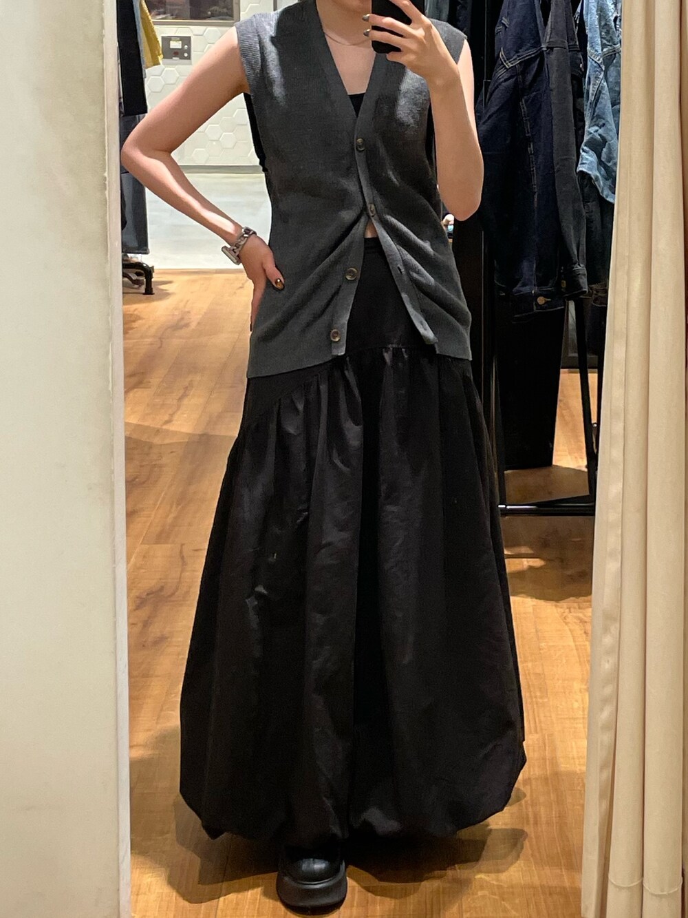 ブラック系のスカート、ブラック系のブーツ、グレー系のベストを着用したレディースの秋コーディネートの3枚目の写真