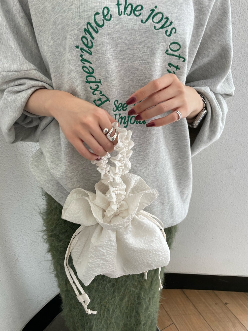 ホワイト系のハンドバッグ、ブラック系のブーツ、グレー系のスウェットを着用したレディースの秋コーディネートの5枚目の写真