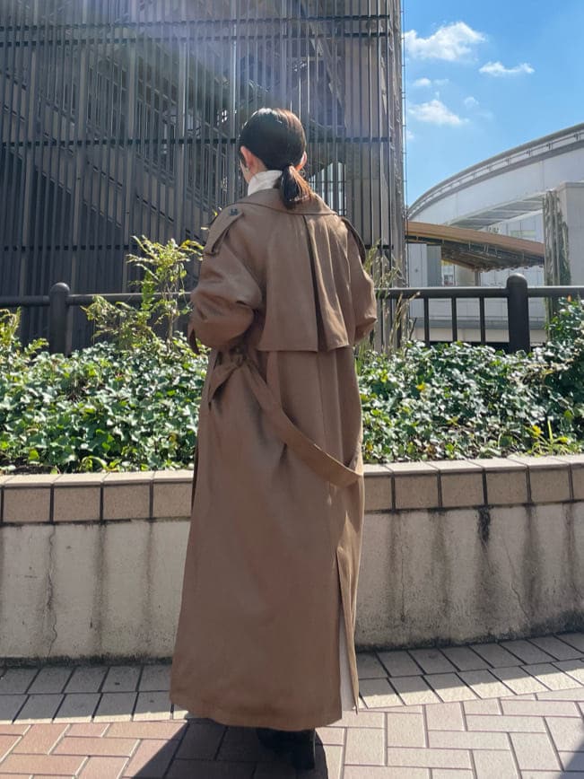 ブラウン系のトレンチコート、ブラック系のブーツ、ホワイト系のワンピースを着用したレディースの秋コーディネートの6枚目の写真