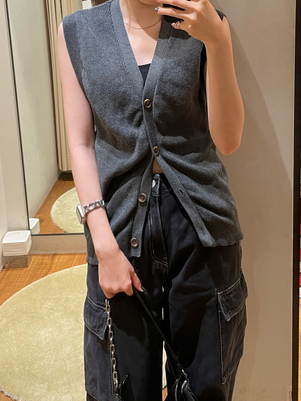 グレー系のベスト、ブラック系のブーツ、ブラック系のデニムパンツを着用したレディースの秋コーディネートの4枚目の写真