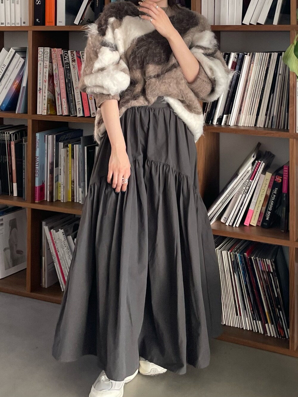 グレー系のスカート、ベージュ系のニット/セーター、ホワイト系のキャップを着用したレディースの秋コーディネートの7枚目の写真