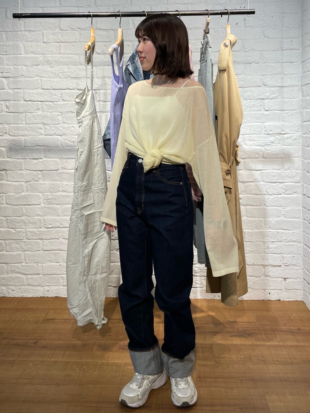 イエロー系のニット/セーター、ブルー系のデニムパンツを着用したレディースの春コーディネートの2枚目の写真