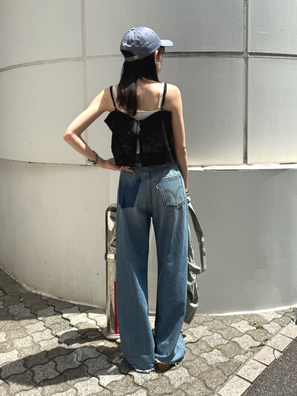 ブラック系のサンダル、グリーン系のトートバッグ、ブルー系のデニムパンツを着用したレディースの夏コーディネートの3枚目の写真