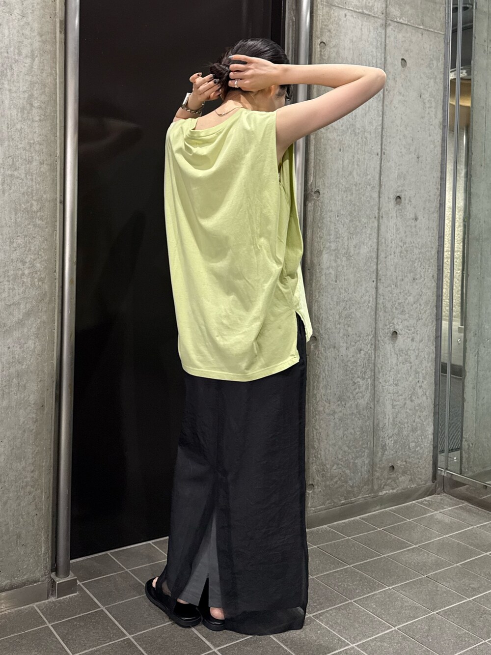 グレー系のスカート、グリーン系のタンクトップ、ブラック系のサンダルを着用したレディースの夏コーディネートの5枚目の写真