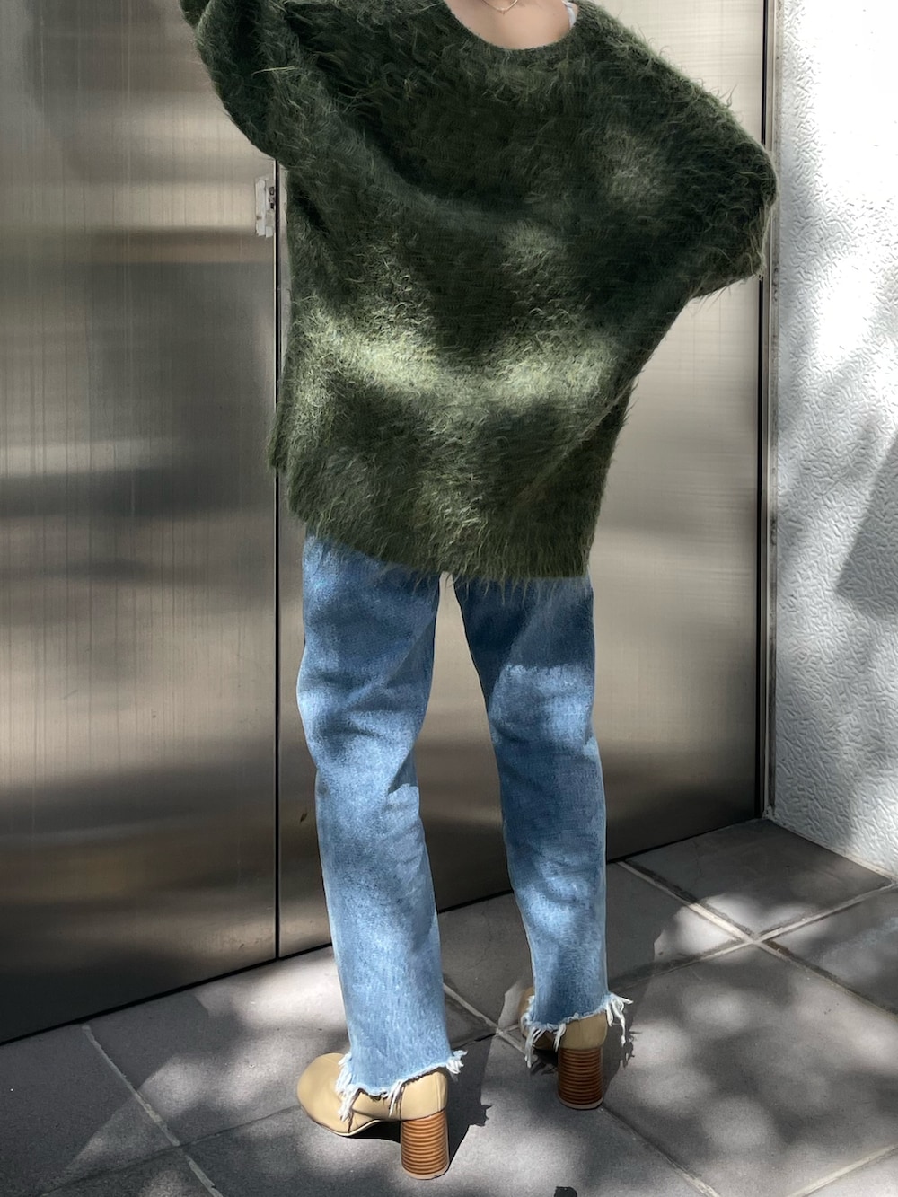 グリーン系のカーディガン/ボレロ、ベージュ系のブーツ、ブルー系のデニムパンツを着用したレディースの秋コーディネートの5枚目の写真