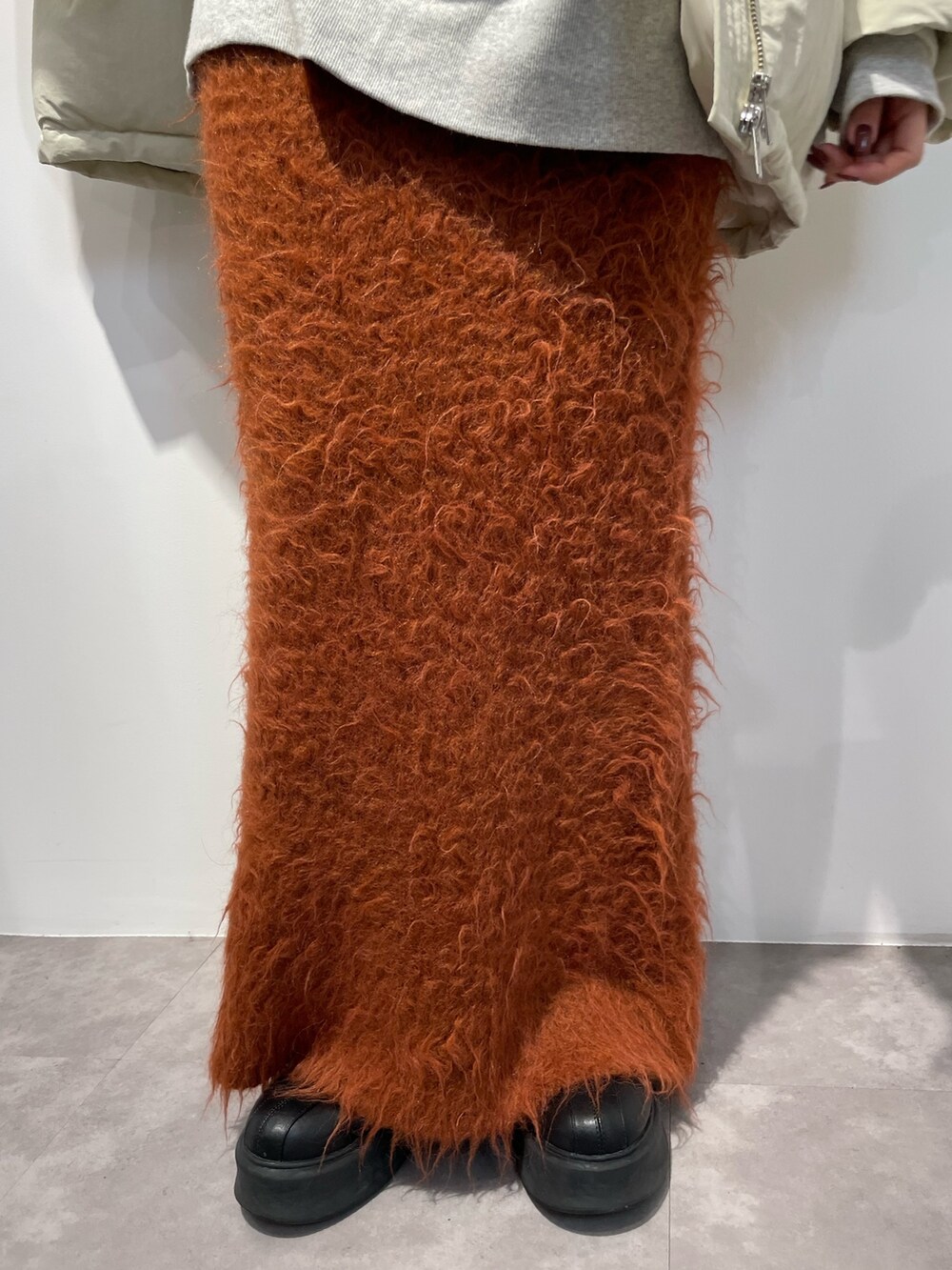 ブラック系のブーツ、ホワイト系のダウンジャケット/コート、オレンジ系のスカートを着用したレディースの秋コーディネートの7枚目の写真