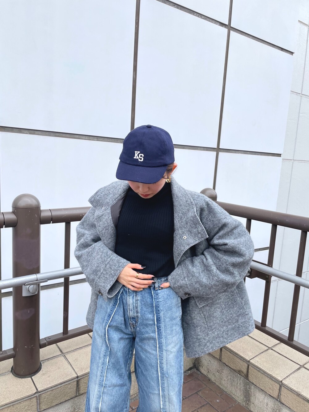 ブルー系のデニムパンツ、ホワイト系のブーツ、グリーン系のクラッチバッグを着用したレディースの秋コーディネートの6枚目の写真