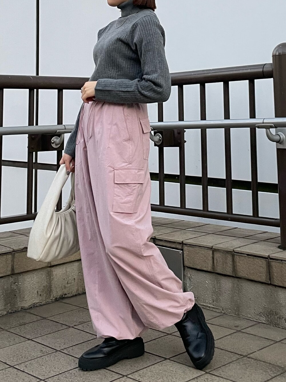 ピンク系のカーゴパンツ、ホワイト系のハンドバッグ、グレー系のニット/セーターを着用したレディースの冬コーディネートの4枚目の写真