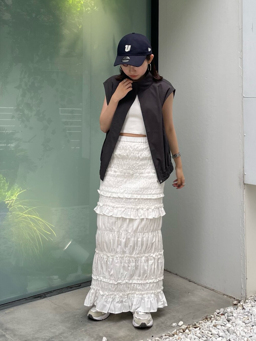 グレー系のベスト、ホワイト系のスカート、ブルー系のキャップを着用したレディースの夏コーディネートの7枚目の写真