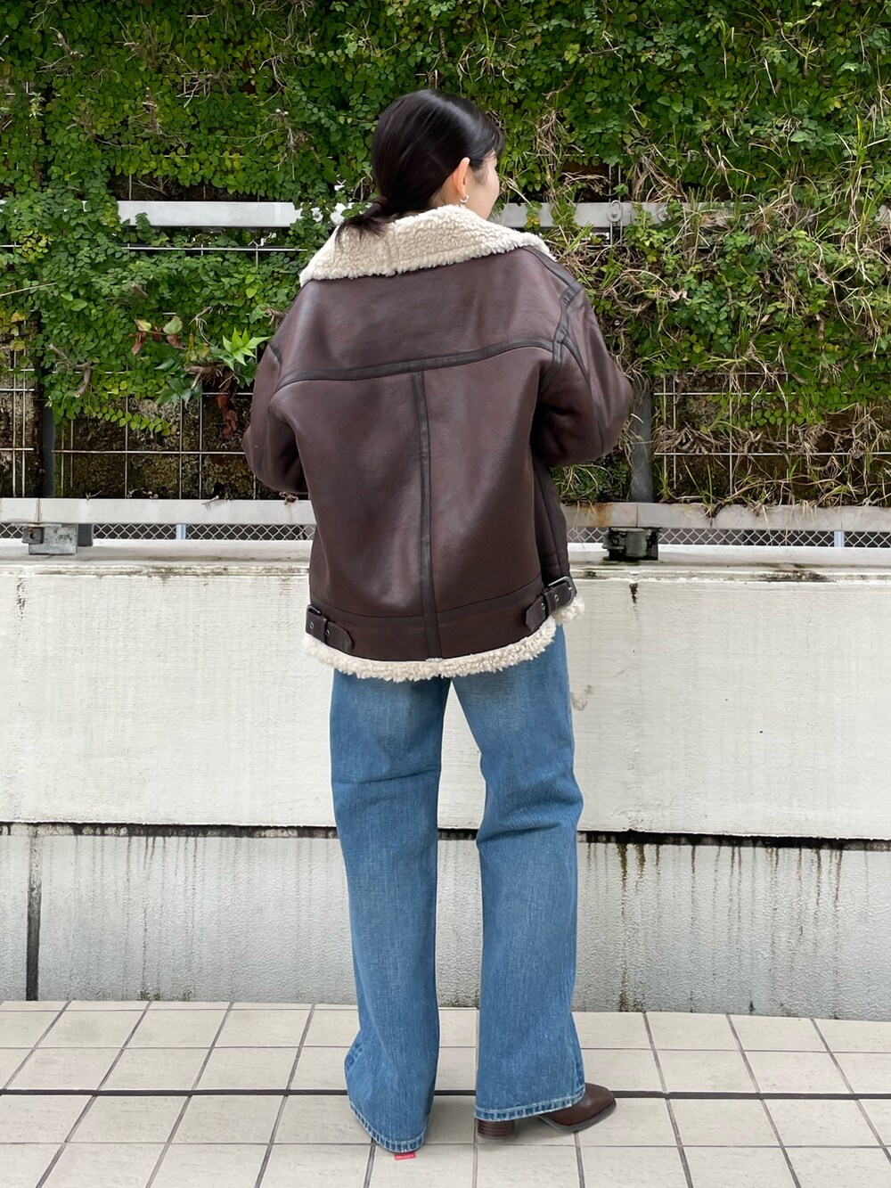 ブルー系のデニムパンツ、ブラウン系のブーツ、ベージュ系のハンドバッグを着用したレディースの秋コーディネートの4枚目の写真