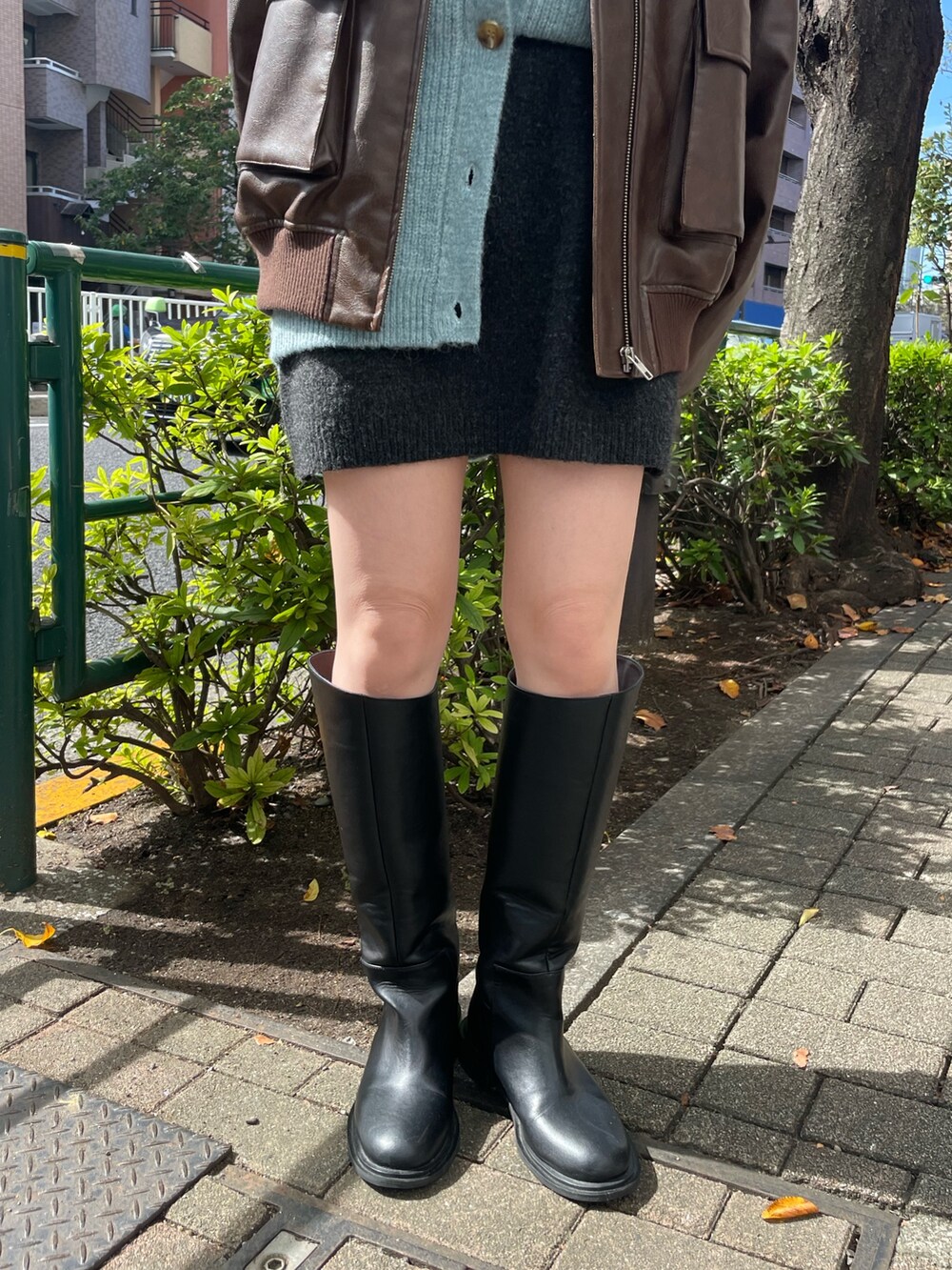 グレー系のスカート、ブラック系のブーツ、ブラウン系のブルゾンを着用したレディースの秋コーディネートの7枚目の写真