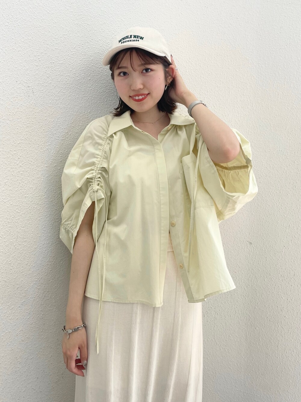 イエロー系のシャツ/ブラウス、ホワイト系のキャミソール、ホワイト系のスカートを着用したレディースの春コーディネートの2枚目の写真