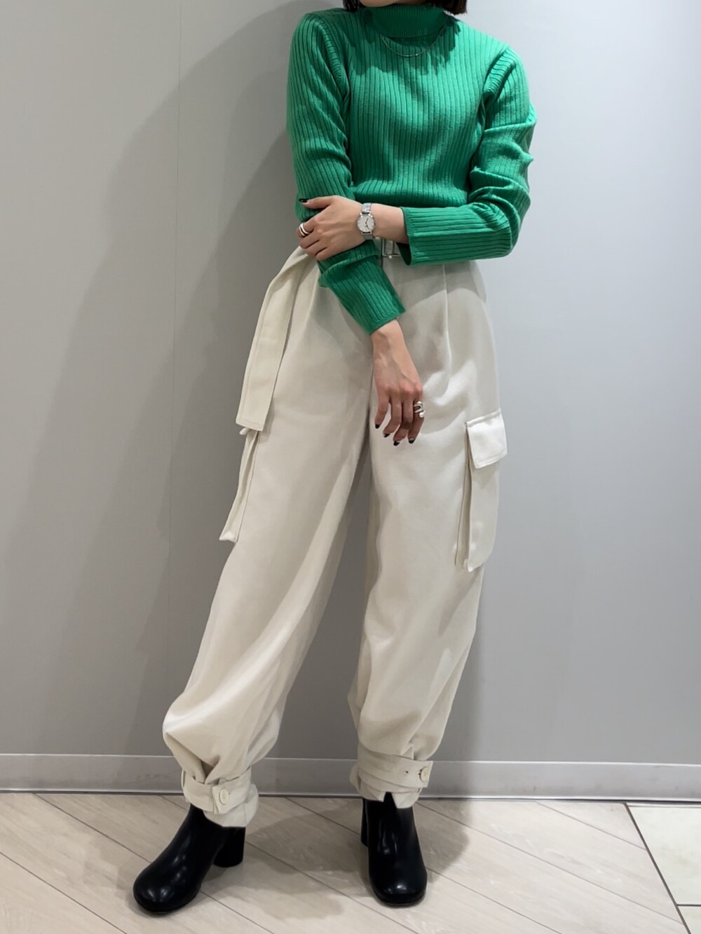 ブラック系のブーツ、ホワイト系のカーゴパンツ、グリーン系のニット/セーターを着用したレディースの冬コーディネートの2枚目の写真