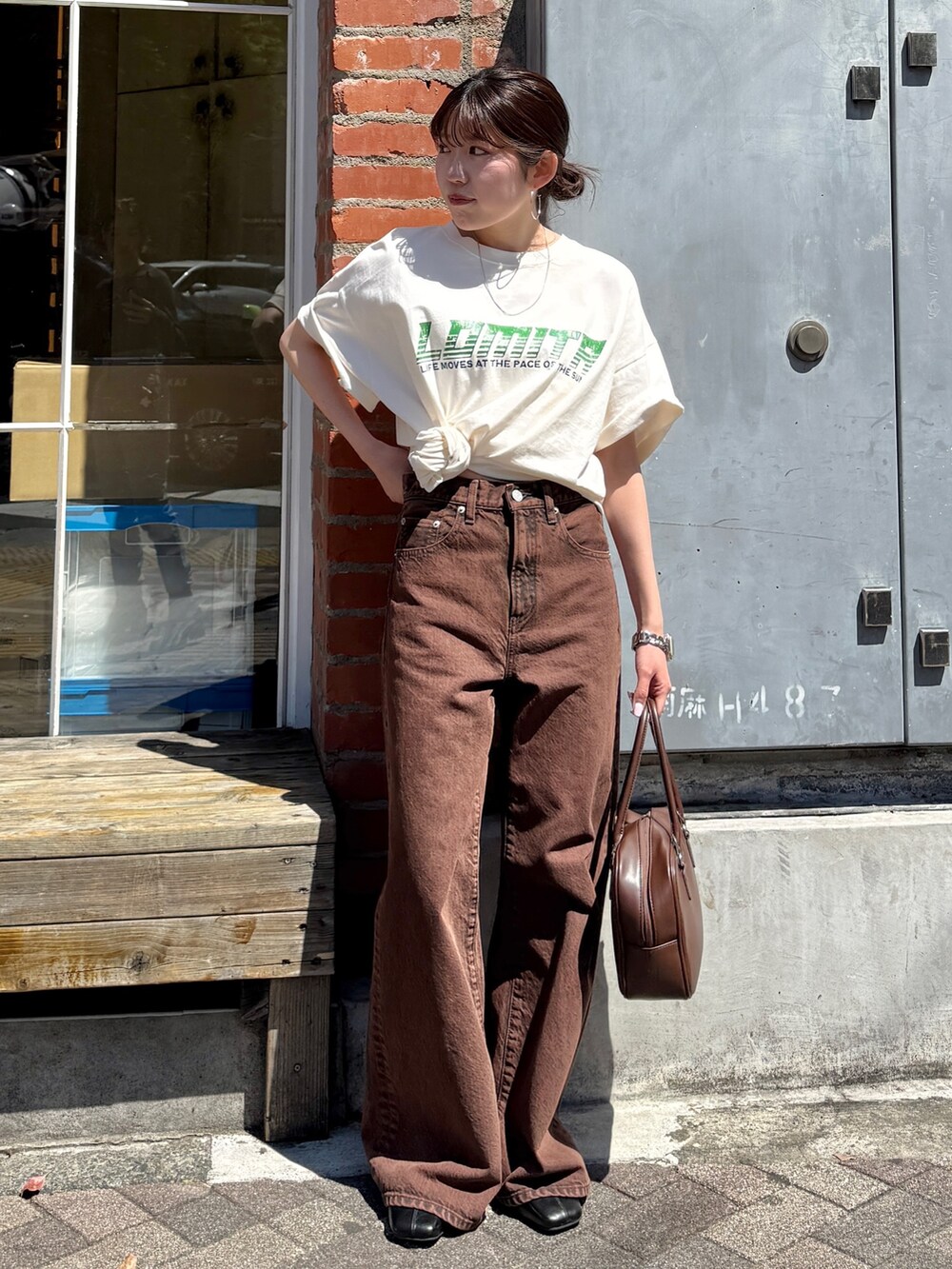 ホワイト系のTシャツ/カットソー、ブラウン系のデニムパンツ、ブラック系のサンダルを着用したレディースの春コーディネートの6枚目の写真