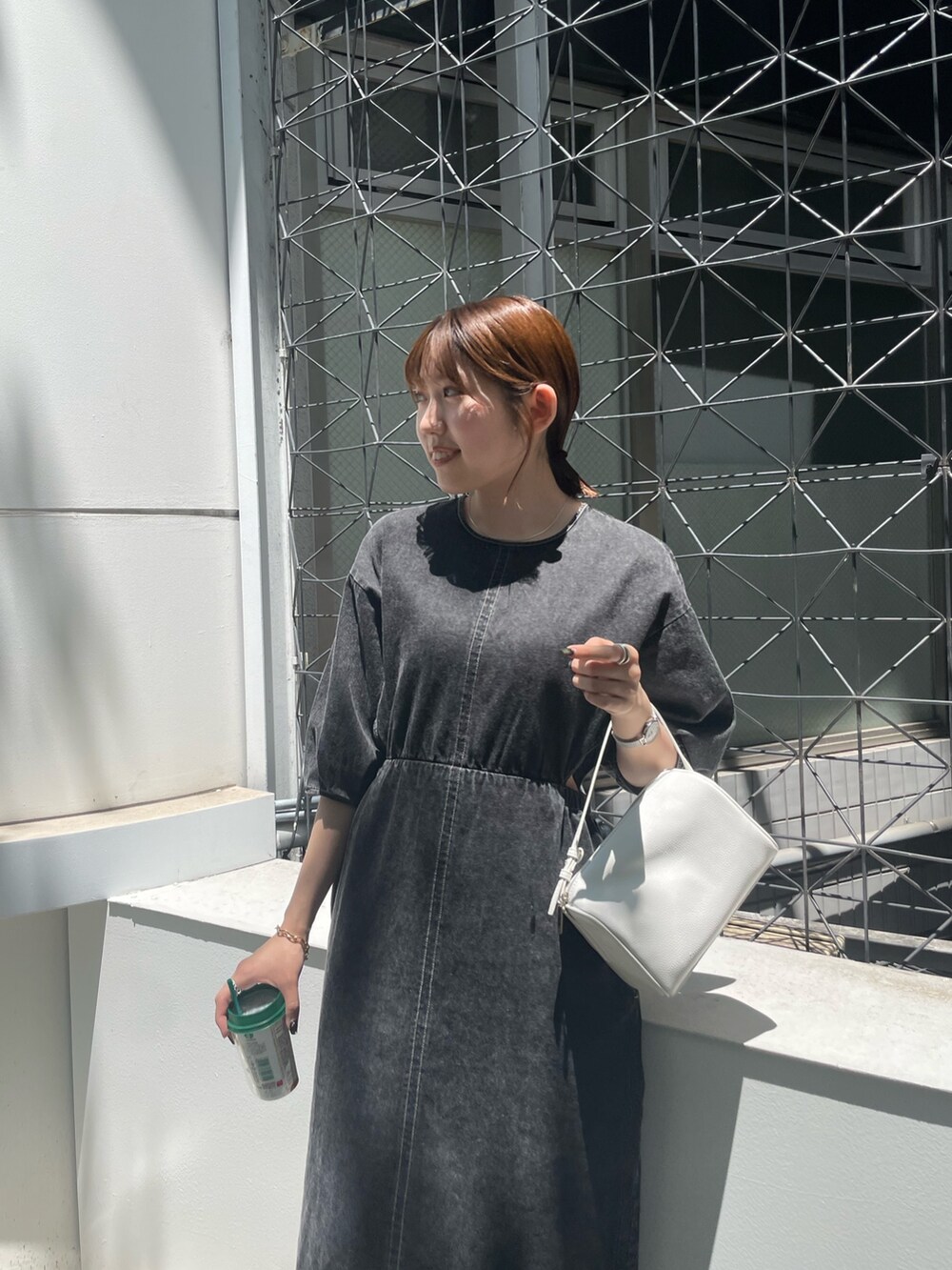 ホワイト系のハンドバッグ、ブラック系のブーツ、ブラック系のワンピースを着用したレディースの夏コーディネートの4枚目の写真