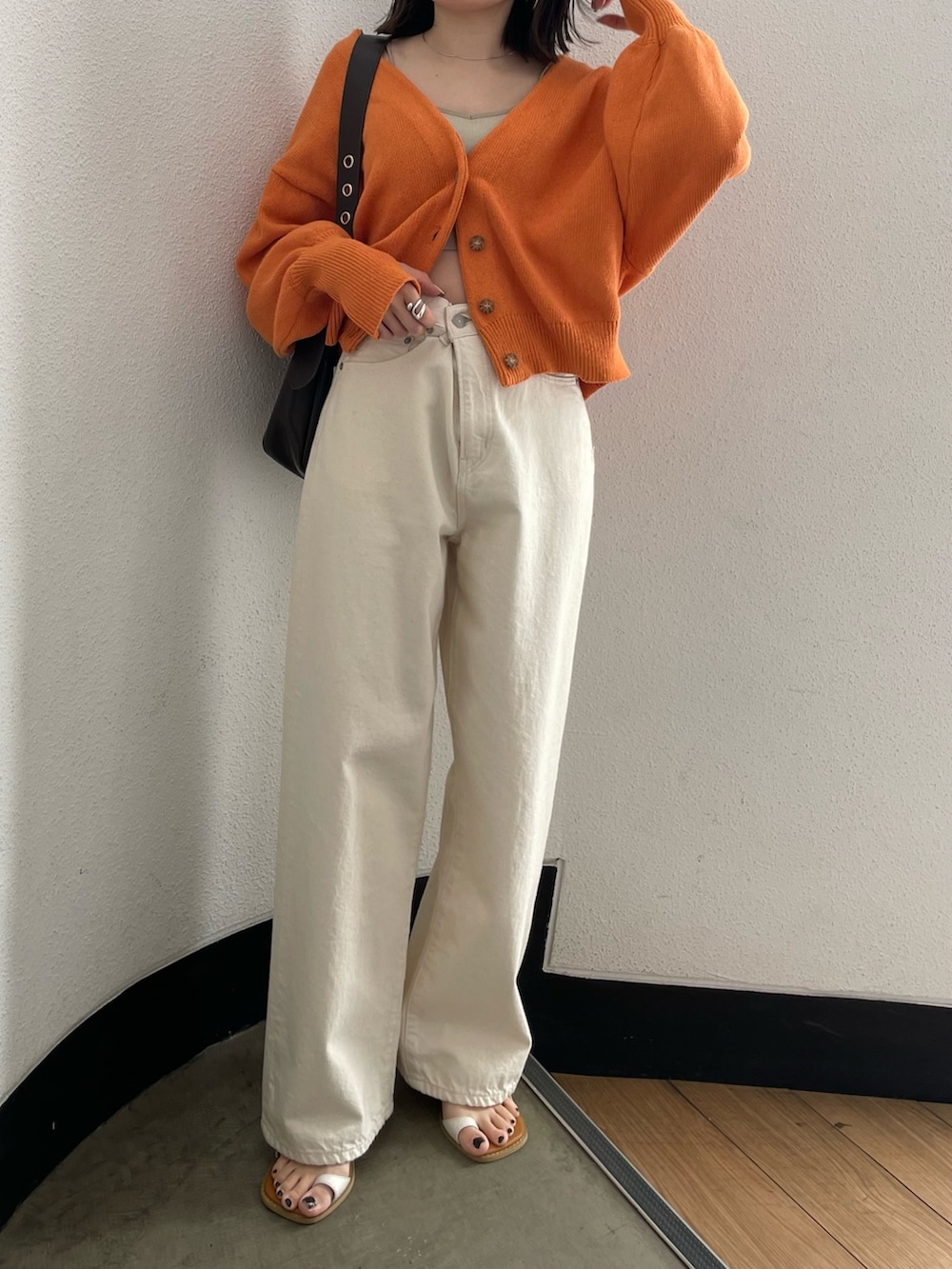 グレー系のキャミソール、ホワイト系のデニムパンツ、ホワイト系のサンダルを着用したレディースの春コーディネートの2枚目の写真