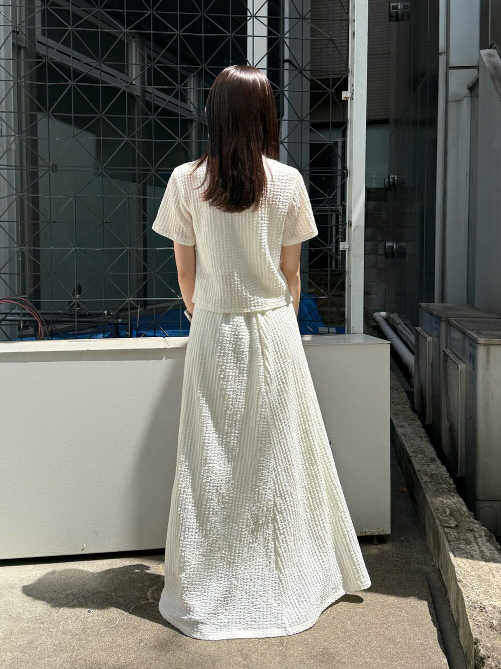 ホワイト系のポロシャツ、ホワイト系のスカート、ブラウン系のハンドバッグを着用したレディースの夏コーディネートの3枚目の写真