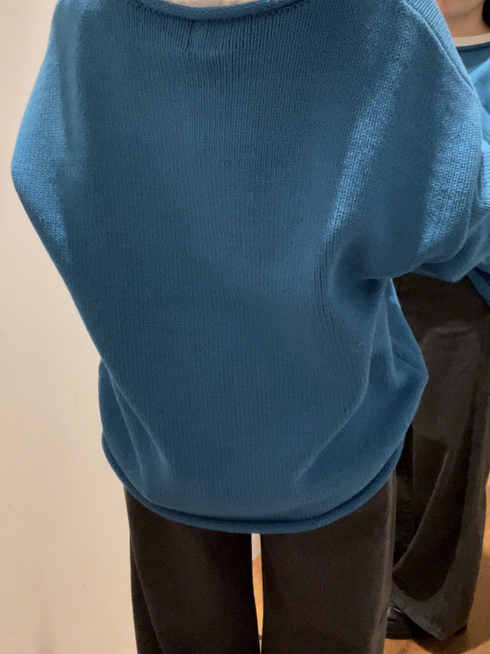 ブラック系のデニムパンツ、ブルー系のニット/セーター、ホワイト系のTシャツ/カットソーを着用したレディースの秋コーディネートの5枚目の写真