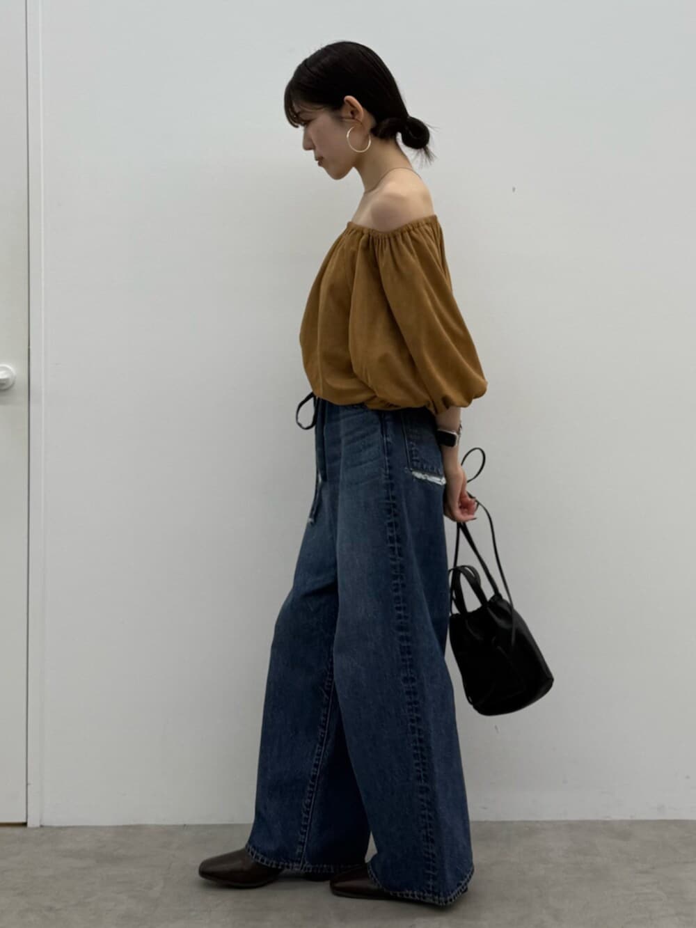 ブラウン系のブーツ、ブラック系のショルダーバッグ、ブルー系のデニムパンツを着用したレディースの秋コーディネートの3枚目の写真