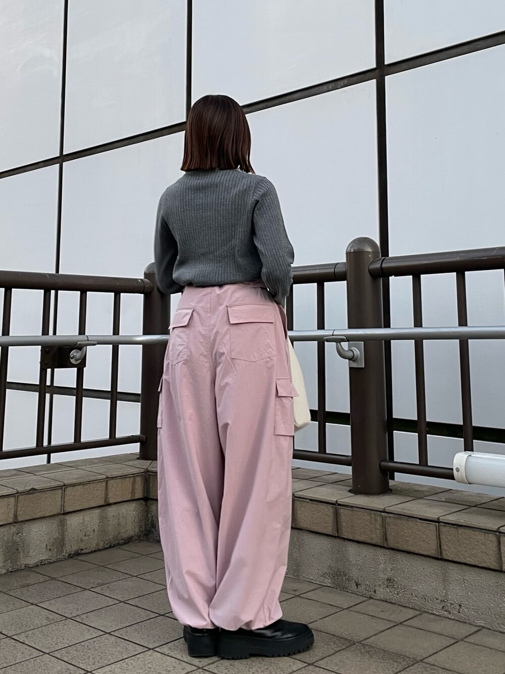 ピンク系のカーゴパンツ、ホワイト系のハンドバッグ、グレー系のニット/セーターを着用したレディースの冬コーディネートの5枚目の写真