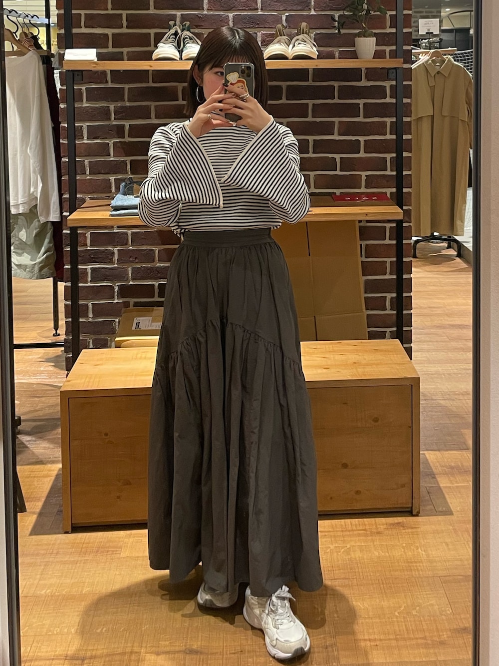 グレー系のスカート、ホワイト系のニット/セーター、シルバー系のショルダーバッグを着用したレディースの冬コーディネートの2枚目の写真