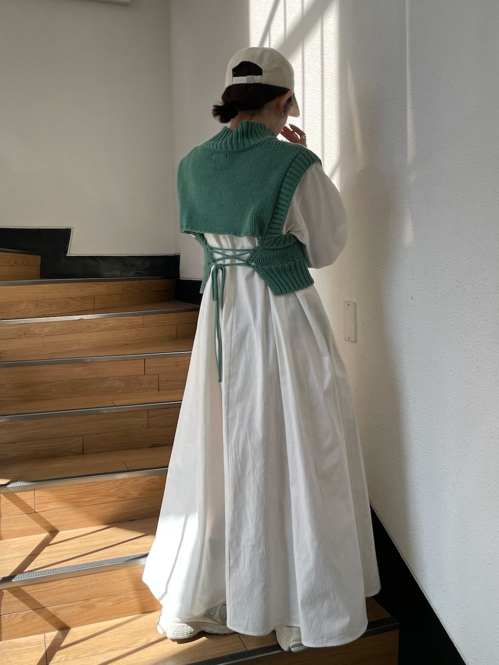グリーン系のワンピース、ホワイト系のキャップを着用したレディースの春コーディネートの2枚目の写真