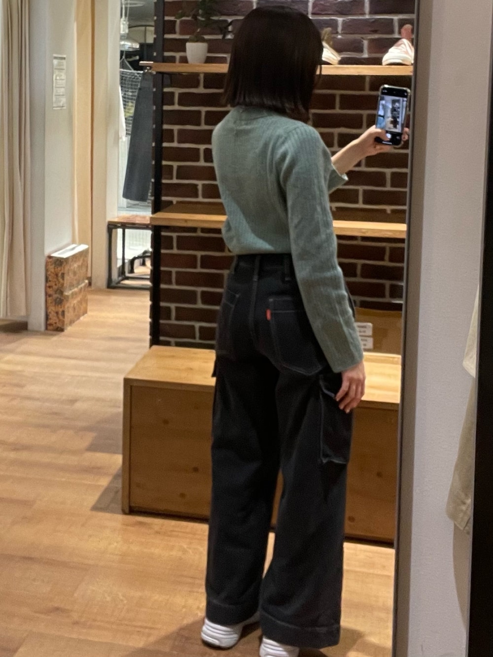 グリーン系のニット/セーター、ブラック系のショルダーバッグ、ブラック系のデニムパンツを着用したレディースの冬コーディネートの5枚目の写真