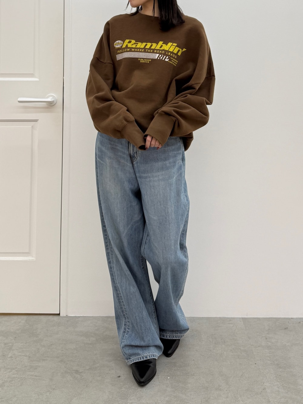 ブルー系のデニムパンツ、ブラック系のブーツ、ブラウン系のスウェットを着用したレディースの秋コーディネートの2枚目の写真
