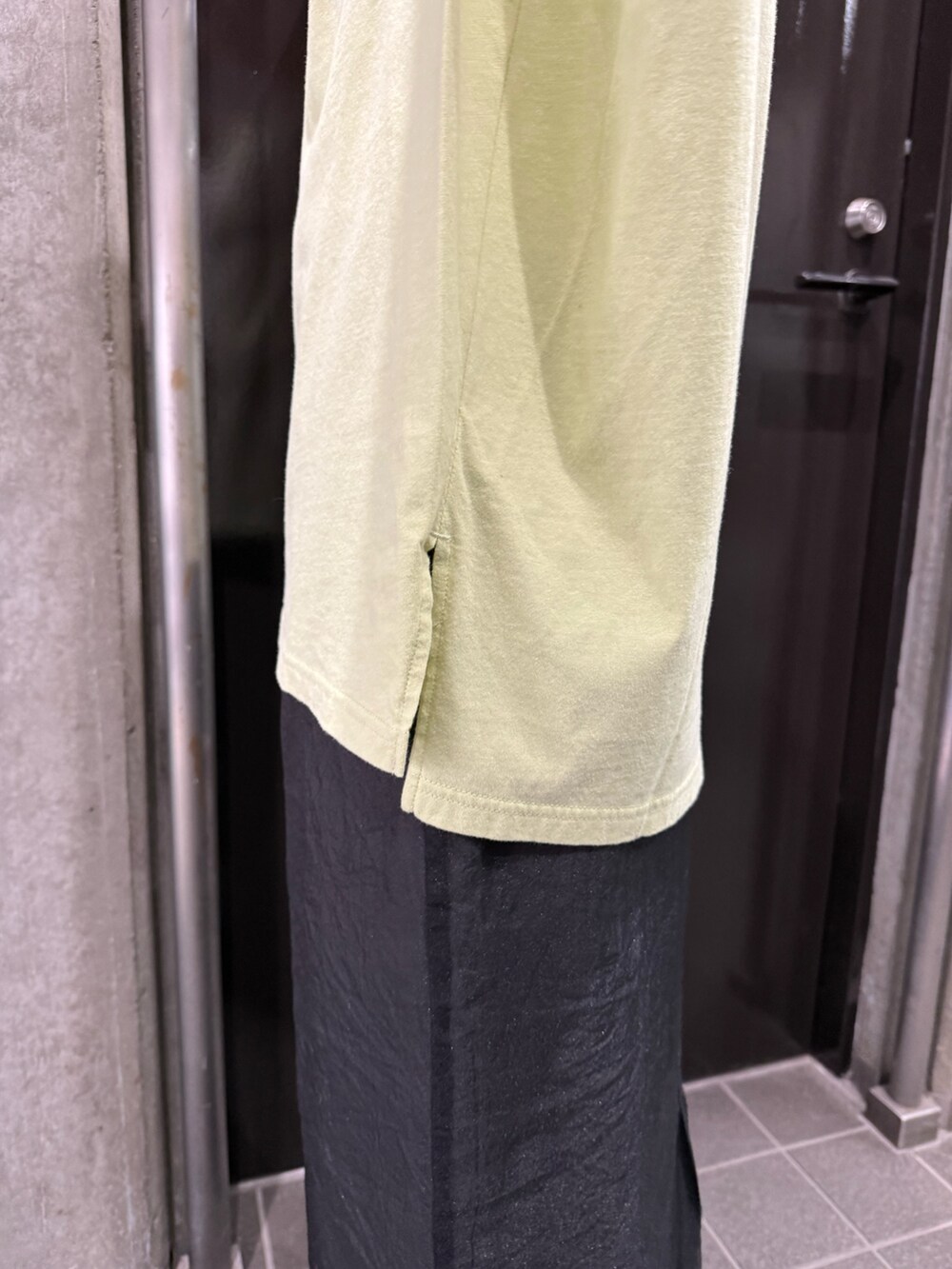 グレー系のスカート、グリーン系のタンクトップ、ブラック系のサンダルを着用したレディースの夏コーディネートの8枚目の写真