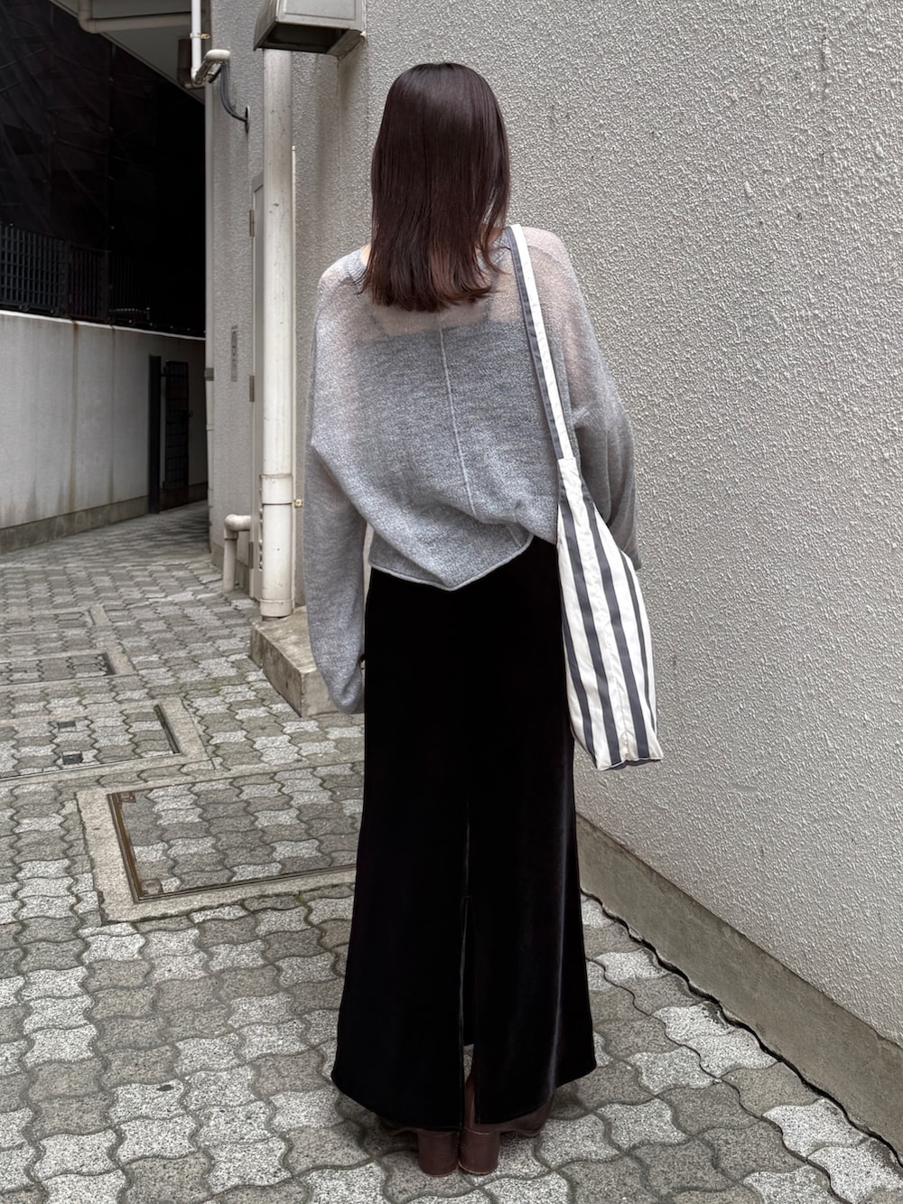 ブラック系のスカート、ブラウン系のブーツ、グレー系のニット/セーターを着用したレディースの秋コーディネートの5枚目の写真