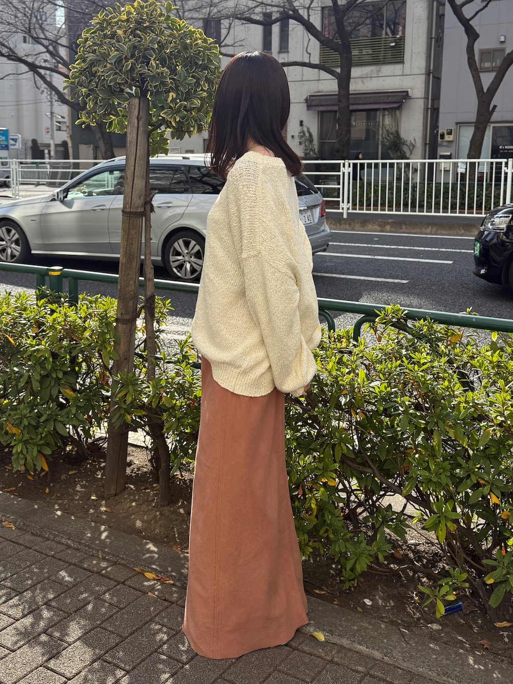 オレンジ系のスカート、ホワイト系のニット/セーターを着用したレディースの冬コーディネートの3枚目の写真