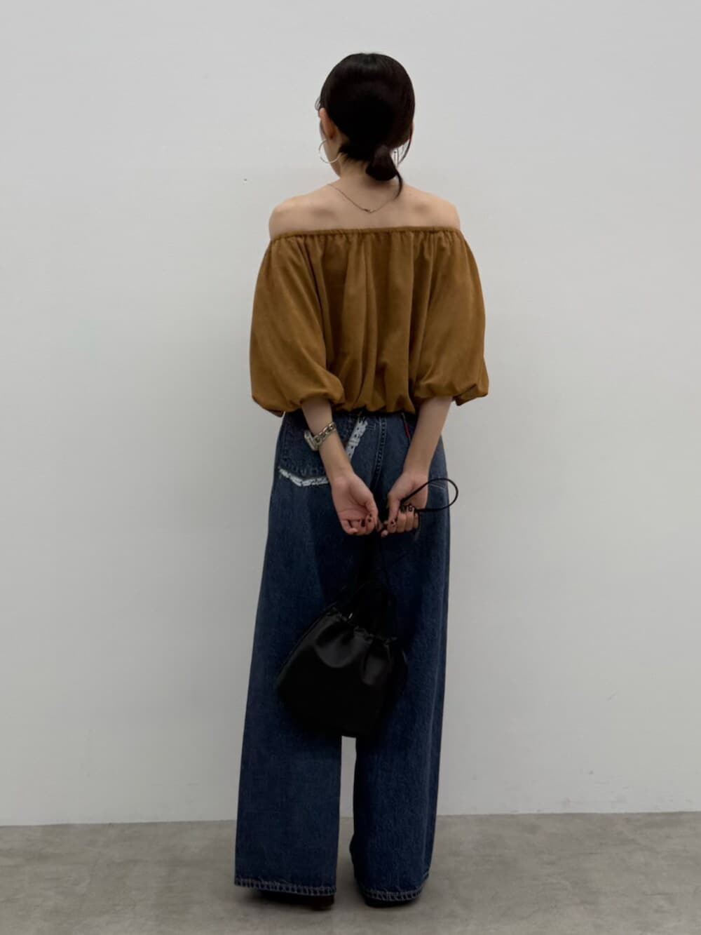 ブラウン系のブーツ、ブラック系のショルダーバッグ、ブルー系のデニムパンツを着用したレディースの秋コーディネートの4枚目の写真