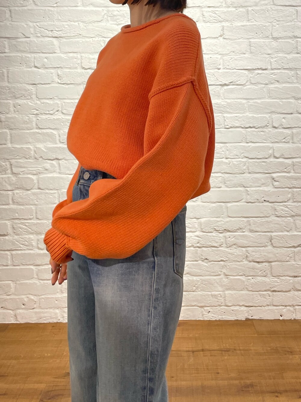 オレンジ系のニット/セーター、ブルー系のデニムパンツ、ブラック系のブーツを着用したレディースの冬コーディネートの5枚目の写真