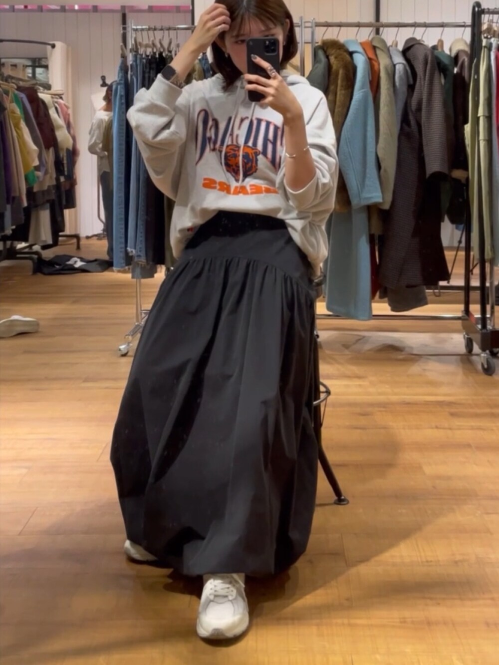 ブラック系のスカート、グレー系のパーカーを着用したレディースの秋コーディネートの2枚目の写真