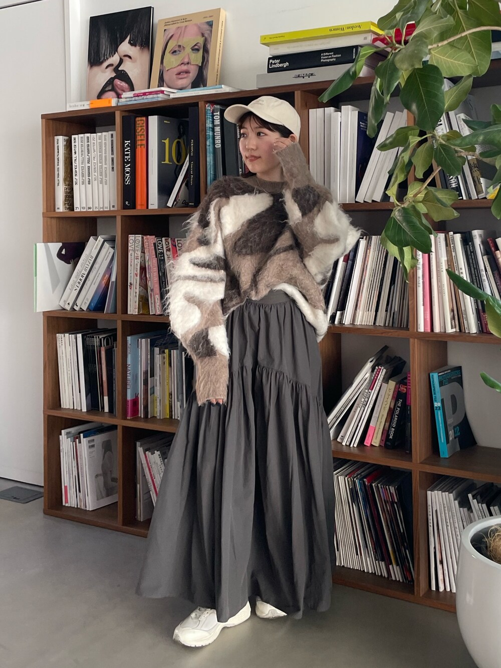 グレー系のスカート、ベージュ系のニット/セーター、ホワイト系のキャップを着用したレディースの秋コーディネートの4枚目の写真