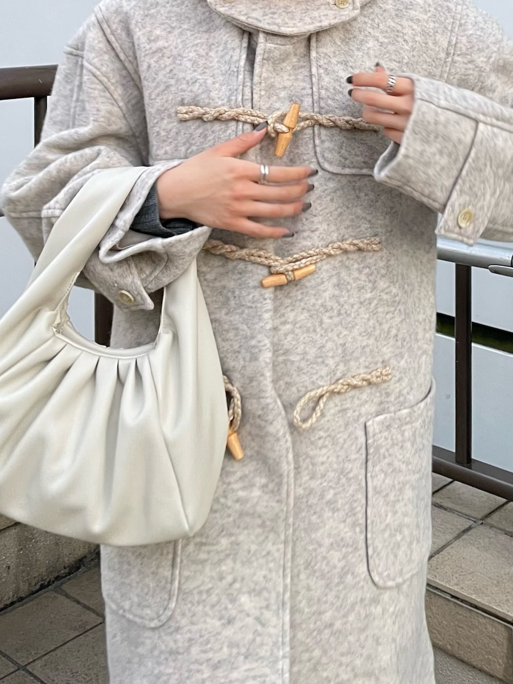 ピンク系のカーゴパンツ、ホワイト系のハンドバッグ、ホワイト系のダッフルコートを着用したレディースの冬コーディネートの2枚目の写真